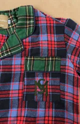 Pijama largo a cuadros de franela en tonos azul, rojo y verde, compuesto por una camisa de manga larga con solapas y botones frontales, y un pantalón largo de corte recto con puños y detalles en tartán verde.