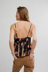 Top estilo babydoll de viscosa color rosado con estampado floreado, escote en V pronunciado, tirantes finos y detalles de volados combinados con paneles en tono crudo.