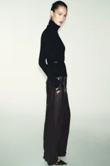Jersey de punto liso confeccionado en 100% lana, con cuello subido y manga larga. Incluye un cinturón fino integrado en la cintura con hebilla metálica.