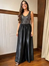 Vestido largo rojo con cuerpo de lentejuelas y falda de satén con caída fluida. Presenta escote redondo, sin mangas y un lazo en la cintura.