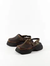 Suecos de cuero color marrón con hebilla lateral y plataforma de goma negra.