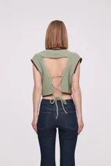 Chaleco corto de punto color marrón con ribete amarillo en cuello, sisas y bajo.