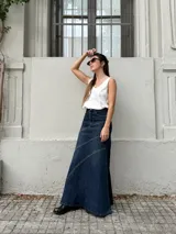 Pollera larga de denim con tiro alto, diseño ajustado en la parte superior y corte acampanado hacia el ruedo. Presenta costuras decorativas en diagonal que aportan movimiento y estructura a la prenda.