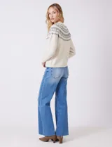 Buzo tejido color blanco con diseño jacquard gris en el canesú, adornado con perlas y cristales de strass. Tiene cuello redondo, mangas ranglan y terminaciones acanaladas en puños y ruedo.