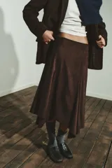 Falda midi de tiro medio con bajo asimétrico y cierre lateral con cremallera oculta. Presenta un acabado texturizado que simula el ante.