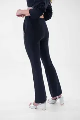 Pantalón negro de corte flare, tiro alto, con detalles de flecos de strass en los bolsillos laterales.