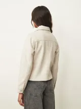 Chaqueta corta de paño color azul oscuro, con cuello camisero, cierre frontal con botones metálicos dorados y bolsillos frontales con solapa.