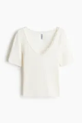 Top en punto acanalado fino de algodón, de color blanco, corte entallado, mangas cortas y escote en V pronunciado ribeteado con encaje.