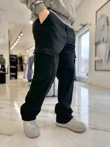 Pantalón cargo de jean negro, de corte ancho y holgado, con bolsillos laterales con solapa.