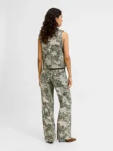 Pantalón de tiro alto, corte recto y amplio, confeccionado en sarga resistente con un estampado all-over camuflado en tonos verde militar y beige, con líneas verticales de pespuntes claros. Cuenta con cierre de cremallera y bolsillos delanteros y traseros.