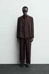 Pantalón de traje straight fit color marrón oscuro, confeccionado en tejido con lana. Cuenta con bolsillos frontales, bolsillos traseros de vivo y cierre frontal con cremallera y gancho metálico oculto.