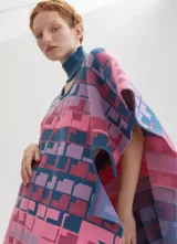 Poncho tejido con cuello alto y aberturas laterales, con diseño geométrico multicolor en tonos rosa, azul y violeta.