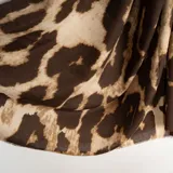 Pashmina de tejido ligero con estampado animal print en tonos marrones y beige, con bordes desflecados.