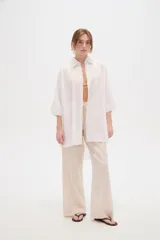 Camisa de lino blanca de corte holgado, con cuello camisero y mangas tres cuartos, diseñada con estilo casual.
