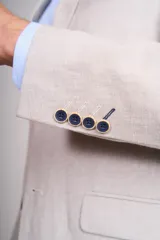 Blazer sport de corte entallado en color celeste, con solapas clásicas, cierre frontal de un botón y bolsillos laterales con solapa. Presenta un pañuelo de bolsillo estampado y botones decorativos en los puños.