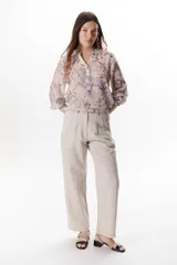 Pantalón de lino color marrón oscuro, tiro alto, corte recto y holgado, con pinzas delanteras y pespuntes a contratono en blanco.