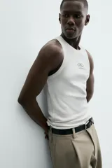 Camiseta tipo tank (sin mangas) de corte relaxed fit, color blanco, con cuello redondo y un pequeño estampado gráfico en el pecho que dice "SANTA BARBARA EST. 1987 CALIFORNIA".