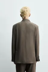 Blazer Zara de corte relajado confeccionada en mezcla de viscosa y lino. Presenta cuello con solapas de pico, cierre frontal de botonadura cruzada, bolsillos de solapa en la cadera y aberturas en la espalda.