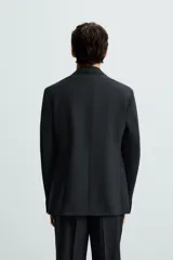 Blazer de corte regular fit confeccionado en tejido con lana. Presenta cuello con solapas de muesca, cierre frontal de dos botones, manga larga con puños abotonados, bolsillo de vivo en el pecho y bolsillos con solapa en la cadera.