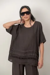 Blusa de lino color blanco, de corte amplio, con escote redondo, mangas cortas y detalle de guarda calada horizontal en la parte inferior.