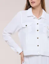 Camperita liviana de corte recto y acabado crepé color blanco, con cuello camisero clásico y cierre frontal de botones metálicos dorados. Presenta bolsillos en el pecho con solapa y mangas largas con puños abotonados.