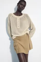 Falda pantalón cruzada de tiro medio en color tostado, con diseño estilo cargo que incluye bolsillos de parche con solapa y detalle de argolla metálica. Cuenta con trabillas y un cinturón integrado con hebilla metálica.