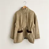 Chaqueta de silueta relajada en tonos beige, confeccionada en una combinación de paño de lana y pana de algodón. Tiene cuello alto, bolsillos amplios con detalles de pana en contraste y cordón regulable en la cintura.