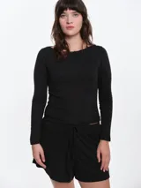 Remera de manga larga entallada en tejido pointelle, con escote bote y detalle de pequeño lazo central. Presenta un acabado con borde picot en el escote.