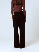 Pantalón de corte sastrero y pierna ancha, color negro, con cintura alta y pinzas frontales.