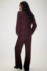 Blazer entallado color bordó con hombreras, solapas clásicas, bolsillos delanteros con solapa y cierre frontal de un botón.