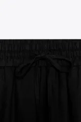 Bermuda color crema confeccionada en lino, de tiro alto con cintura elástica ajustable con cordones y bolsillos delanteros.