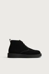 Bota de cordones de piel con acabado en serraje, color negro, con horma redonda y suela con volumen.