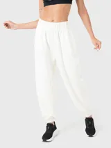 Pantalón de buzo blanco hueso de tela suave, con bolsillos laterales y traseros, y elástico en los tobillos.