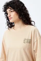 Remera blanca de corte amplio con mangas cortas y estampado con la frase "Unlearn" en el frente y gráfico en la espalda.