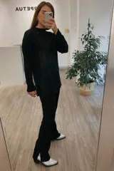 Sweater negro de punto con cuello redondo y diseño trenzado. Corte holgado y largo asimétrico.