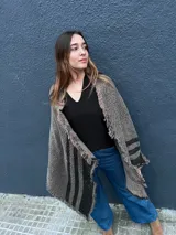 Ruana de lana con diseño a rayas en tonos gris y negro, con detalles de lurex brillante y terminaciones de flecos en los bordes.