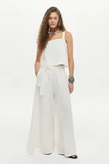 Pantalón palazzo de lino color blanco, de corte amplio con aberturas laterales, cintura elastizada con lazo ajustable y bolsillos.