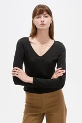 Remera negra de manga larga y calce al cuerpo, confeccionada en poliéster con diseño calado y escote en V.