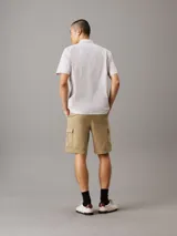 Shorts cargo color beige confeccionados en sarga de algodón elástico, de corte recto y talle medio. Cuenta con cierre de botón y cremallera, cintura elástica en los laterales, bolsillos con ranura en los laterales, bolsillos traseros ribeteados y bolsillos cargo.