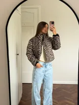 Campera puffer corta con estampado de leopardo, cuello alto y cierre frontal. Diseño acolchado con puños ajustados.
