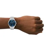 Reloj de pulsera Emporio Armani modelo Dario con caja y malla de acero inoxidable plateado. Presenta una esfera azul con acabado sunray, índices plateados, subesferas de cronógrafo y ventana de fecha a las seis.
