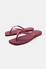 Sandalias planas de dedo tipo ojota, color negro, con diseño minimalista y suela de goma con textura en relieve.