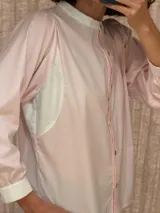 Camisa de algodón color rosado, con cuello mao y detalles en color blanco en el cuello, puños y paneles laterales. Presenta cierre frontal con botones y mangas largas.