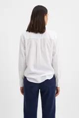 Camisa de manga larga color celeste, con cuello clásico, cierre frontal con botones y un bolsillo aplicado en el pecho.