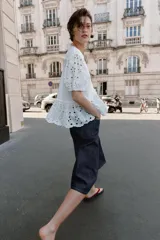 Camiseta blanca de manga corta abullonada y cuello redondo, con detalles de bordados perforados y bajo con doble volante.