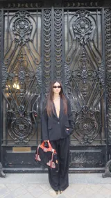 Blazer negro de corte sastrero con diseño de rayas diplomáticas verticales, cierre frontal de un botón y bolsillos laterales con solapa.