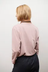 Remera de manga larga en color rosado, con cuello redondo y cierre frontal parcial con botones. Presenta un diseño de corte recto y estilo minimalista.