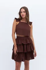 Falda corta marrón oscuro con cintura alta y tres volados superpuestos con efecto arrugado.