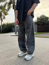 Pantalón de jean con corte baggy, de tiro medio y pierna ancha, con efecto de lavado ácido en tono gris oscuro.