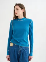 Polera básica de algodón en tejido rib, color turquesa, de manga larga, con hombreras y detalles de pespuntes en color contrastante en las terminaciones y el cuello.